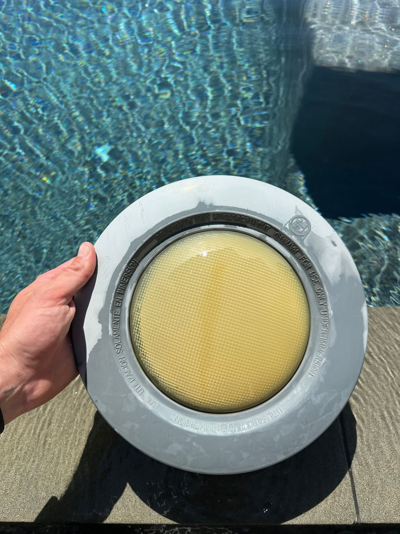 Projecteur de piscine à l'optique jaunie, sorti du bassin