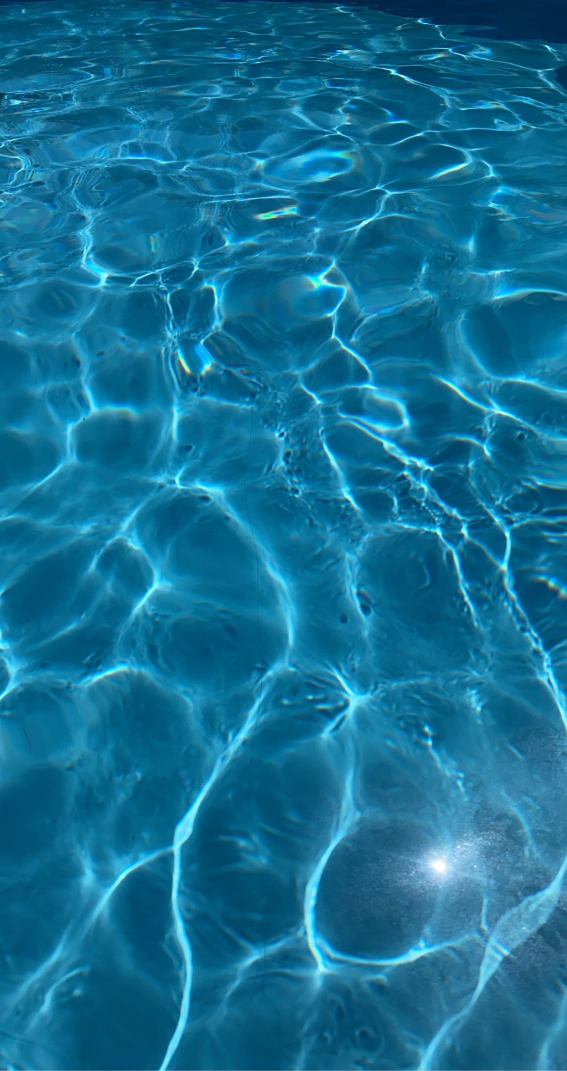 Eau de piscine parfaitement limpide, reflets du soleil sur le fond