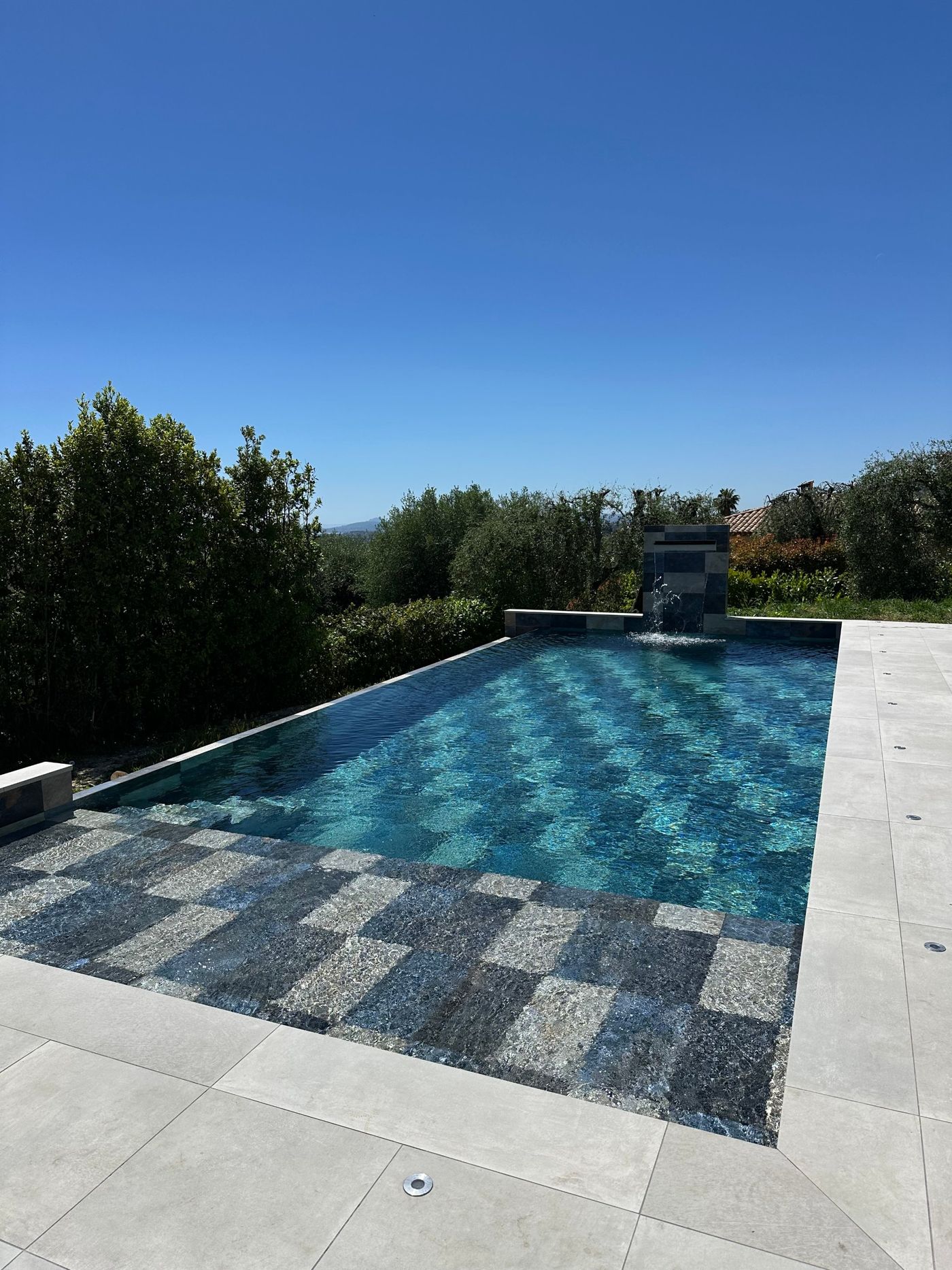 Piscine en pierre de Bali avec cascade, dans un jardin d'oliviers