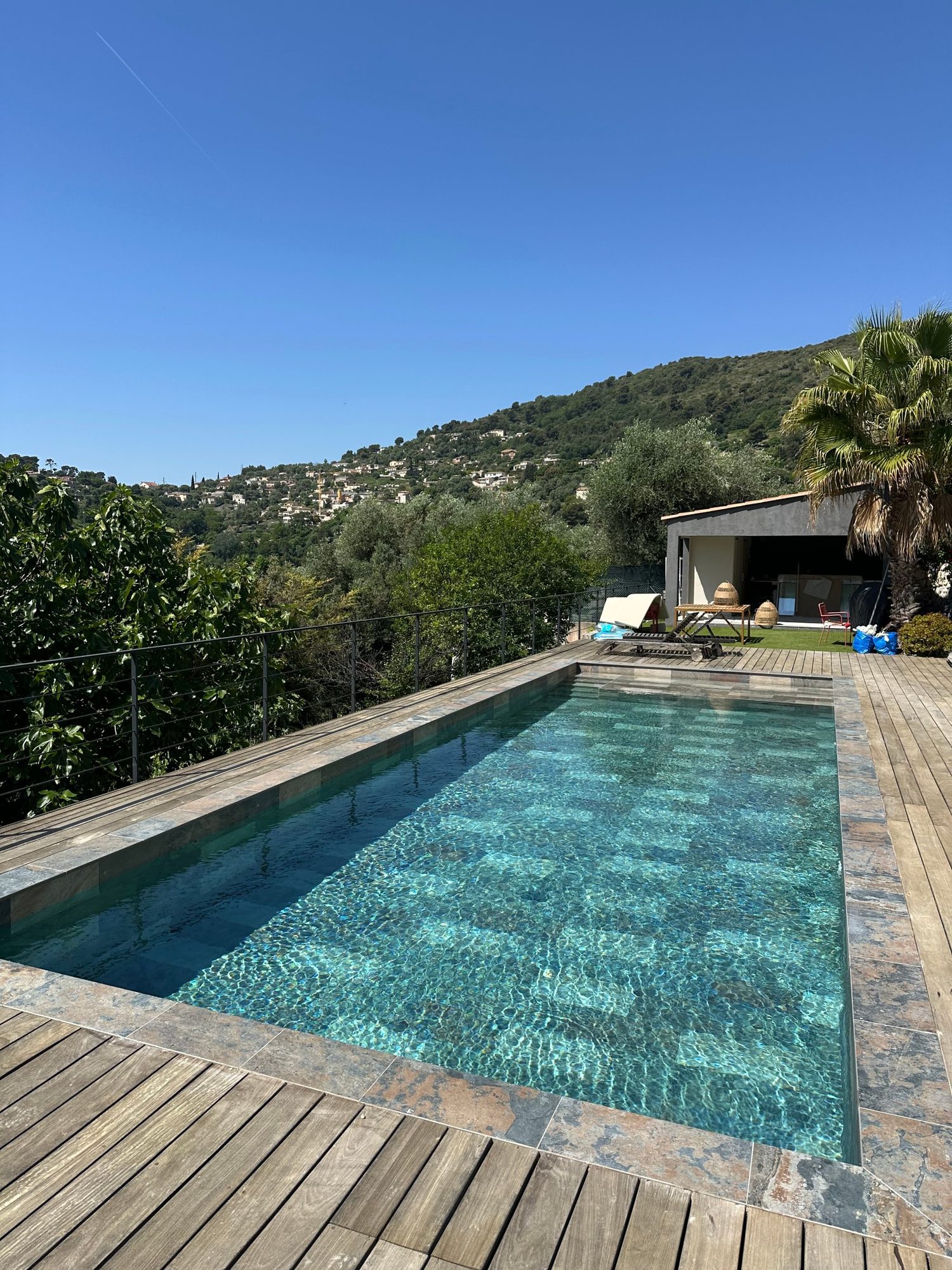 Piscine au revêtement rénové, entourée d'une terrasse en bois face aux collines