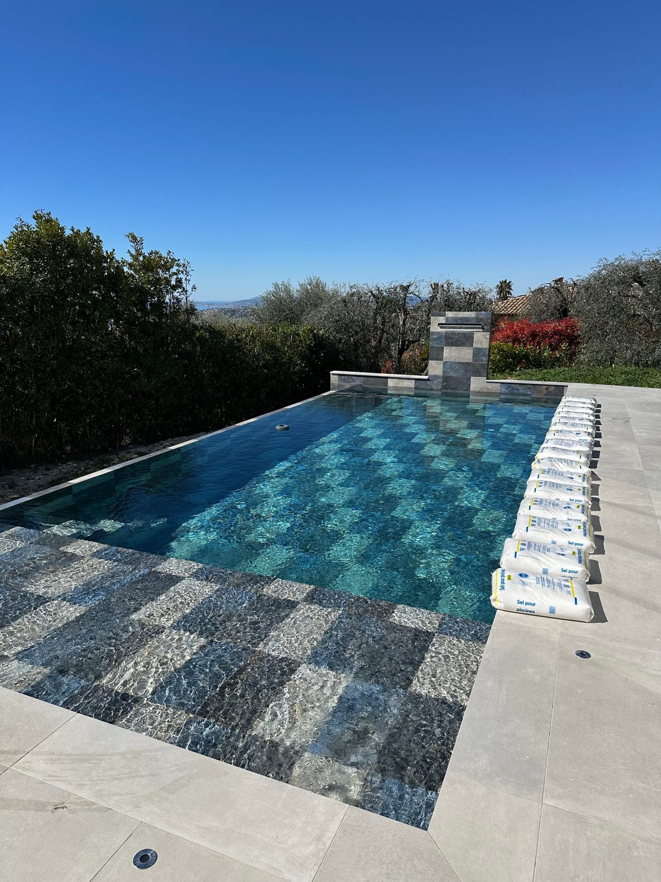 Sacs de sel pour piscine alignés au bord d'un bassin en pierre de Bali